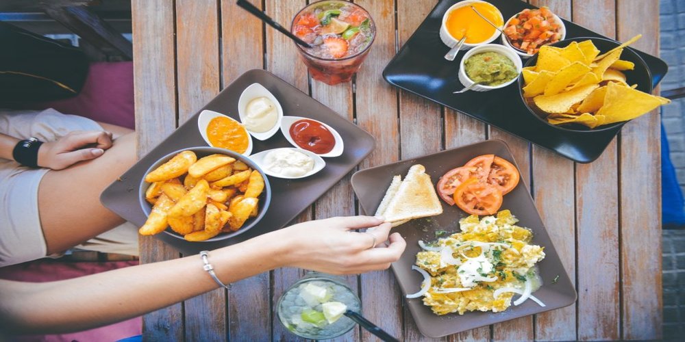 Deep fried snacks, sandwiches and salads with different types of sauce, placed on a table.