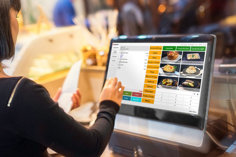 A lady operating the POS at a restaurant and preparing a bill.